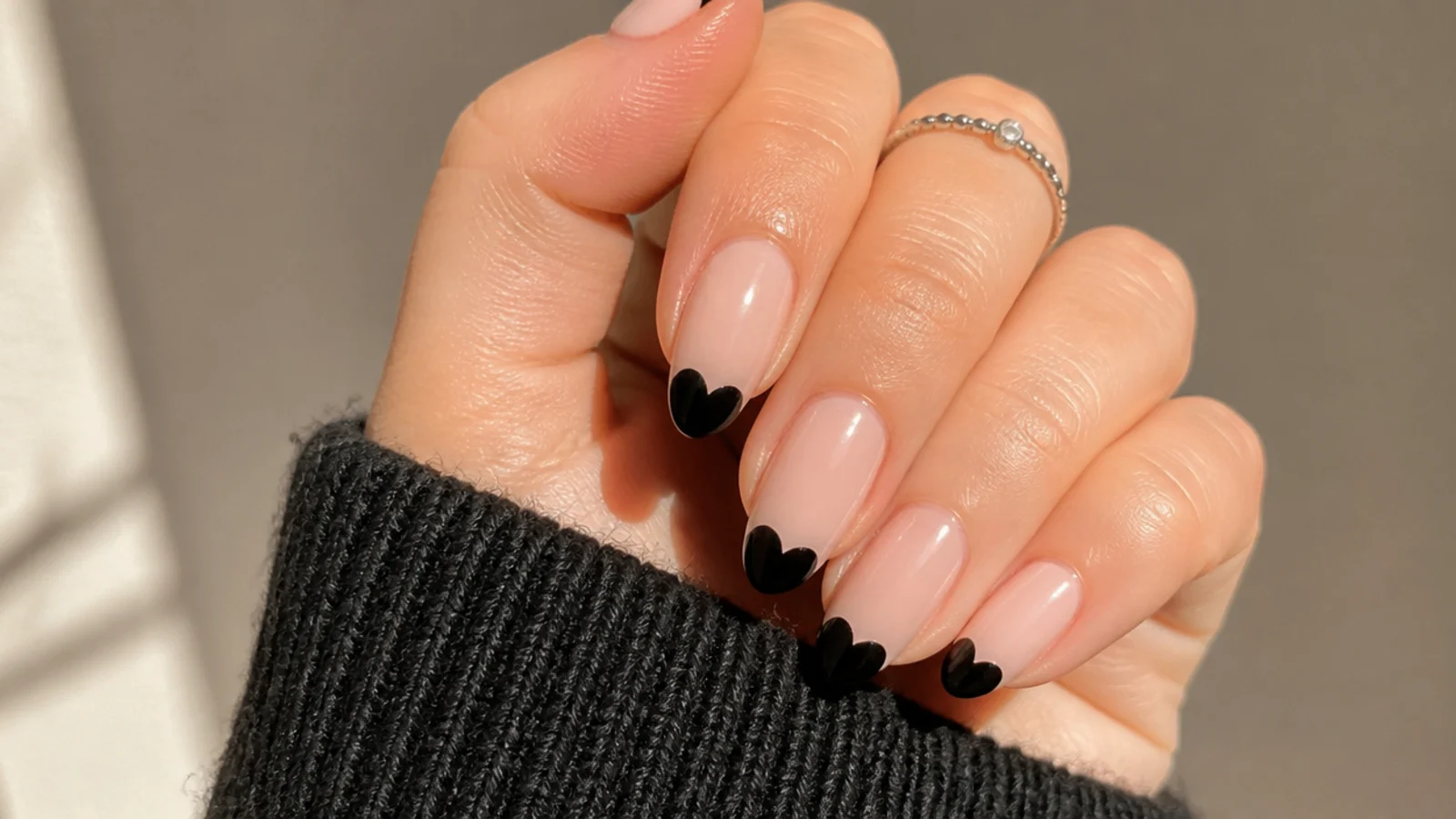 Nude nails with small glossy black heart tips in emo style