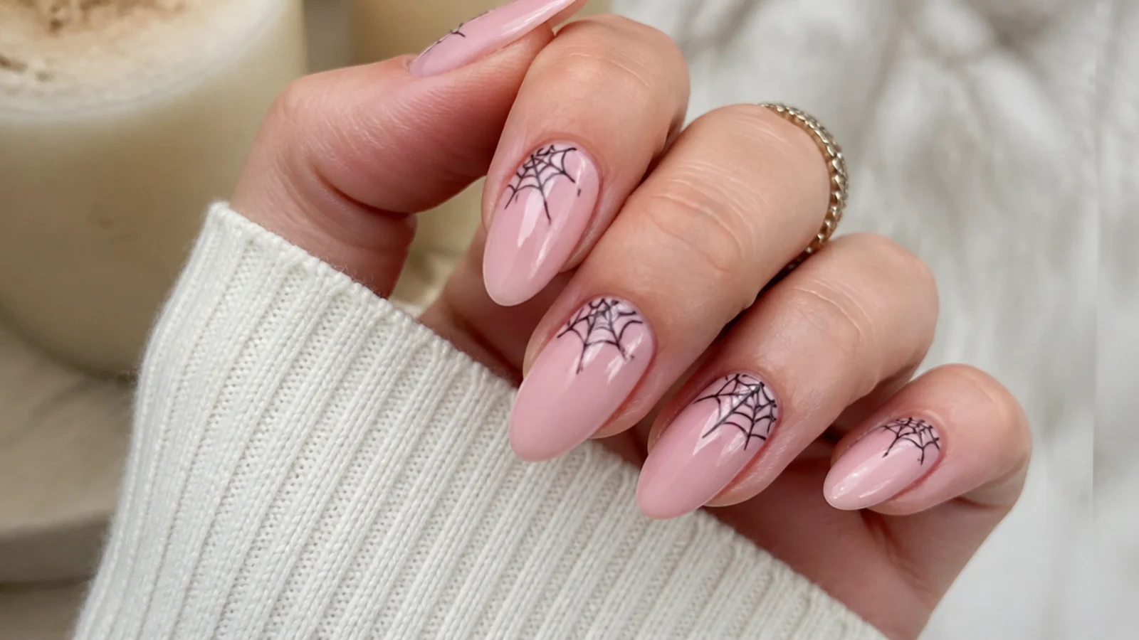 Pink nails with black spiderweb art radiating from the corner