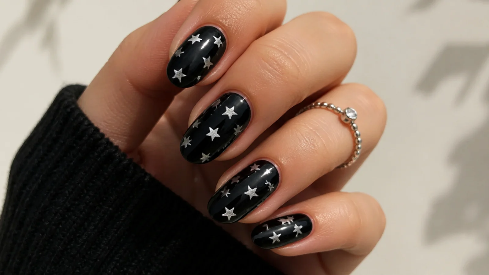 Glossy black nails with small silver and white stars scattered across them