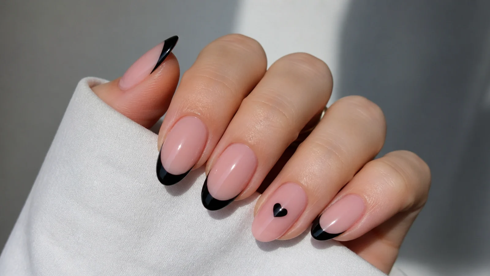 Pink nails with black French tips and a small heart accent