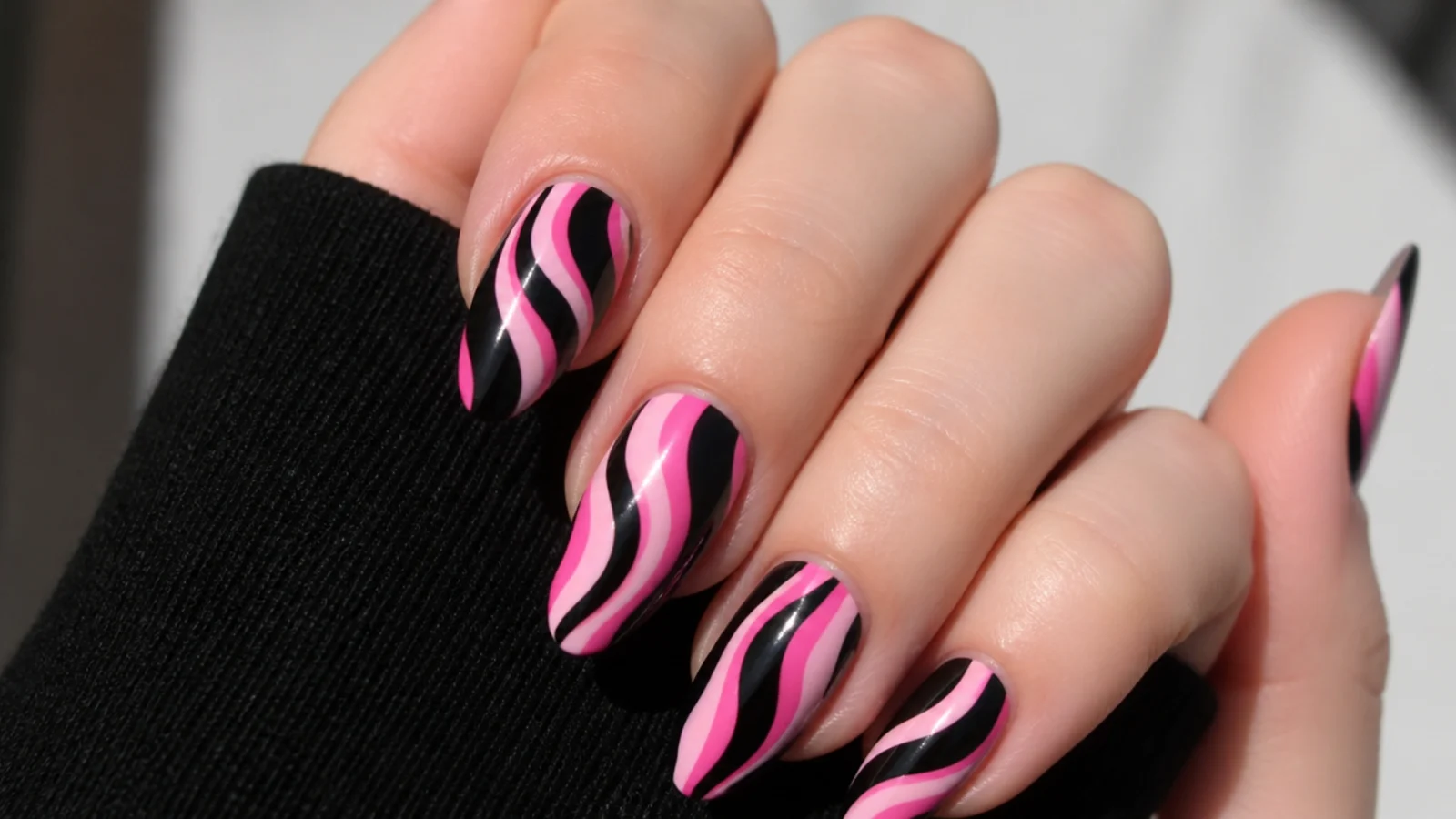 Nails with swirling pink and black wavy stripes in emo style