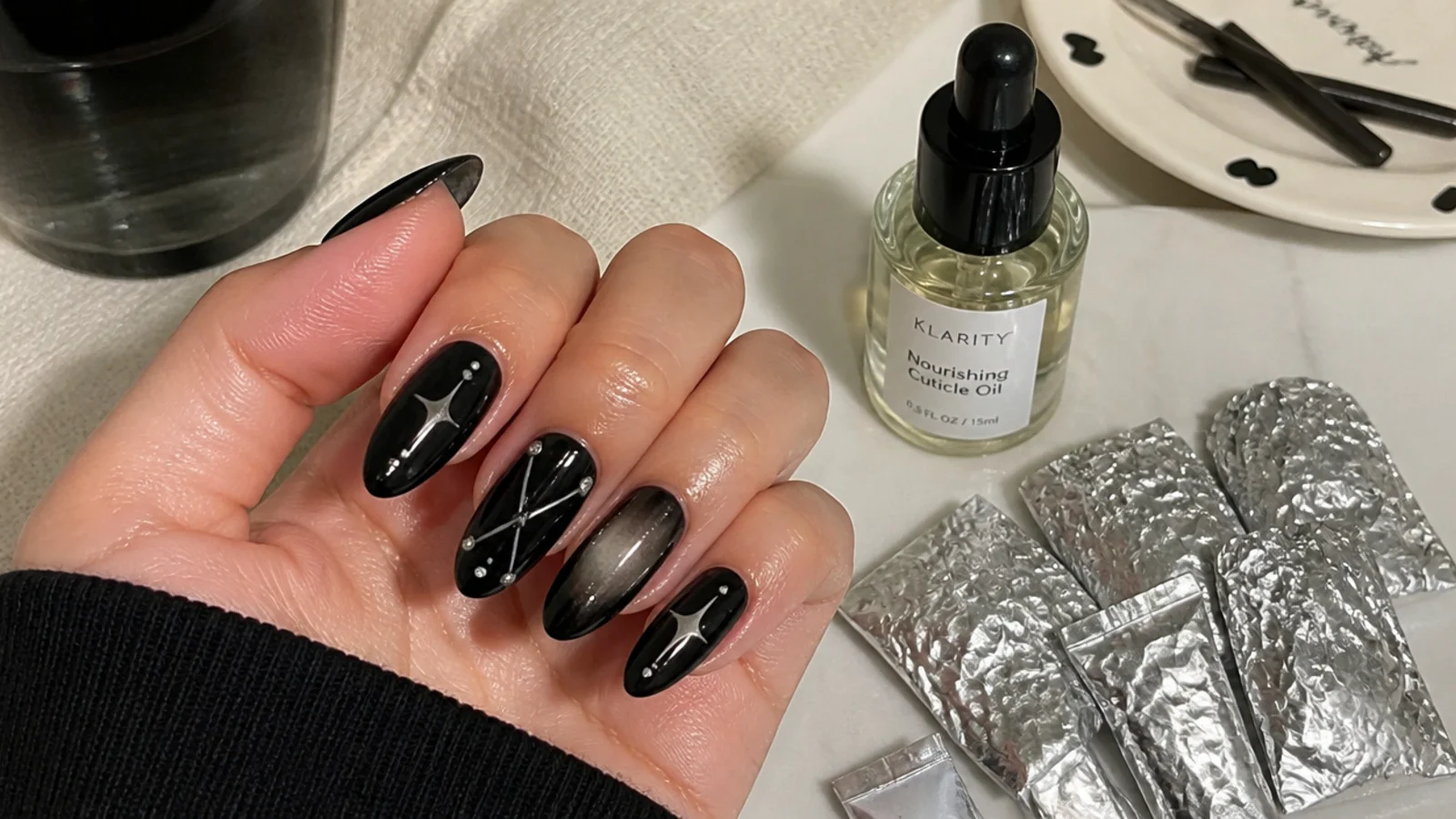 A glossy black emo manicure with cuticle oil and acetone foils for removal