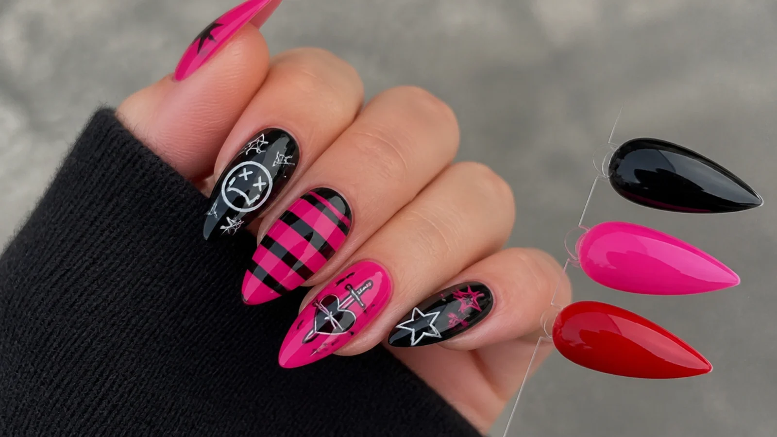 Swatches of black, hot pink and red gel beside emo motif nail art