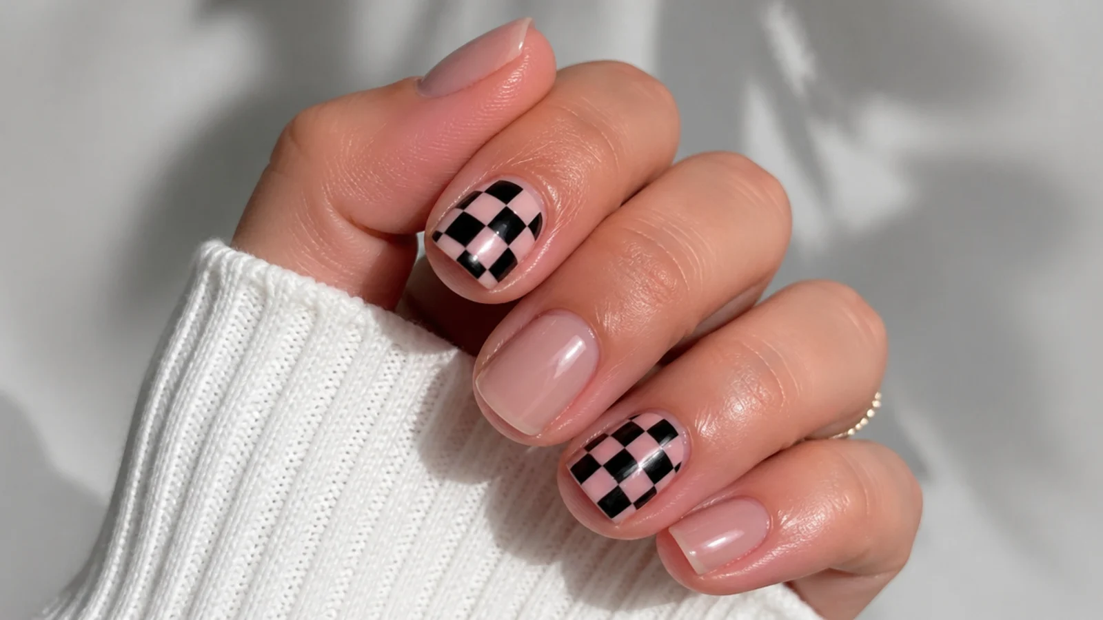 Short nails with a small soft pink and black checkerboard accent