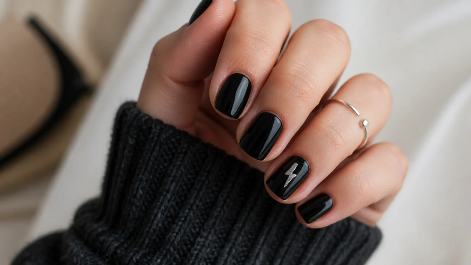 Short black nails with a small silver lightning bolt on one nail