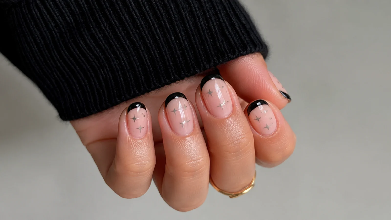 Short nude nails with black tips and tiny silver stars on them