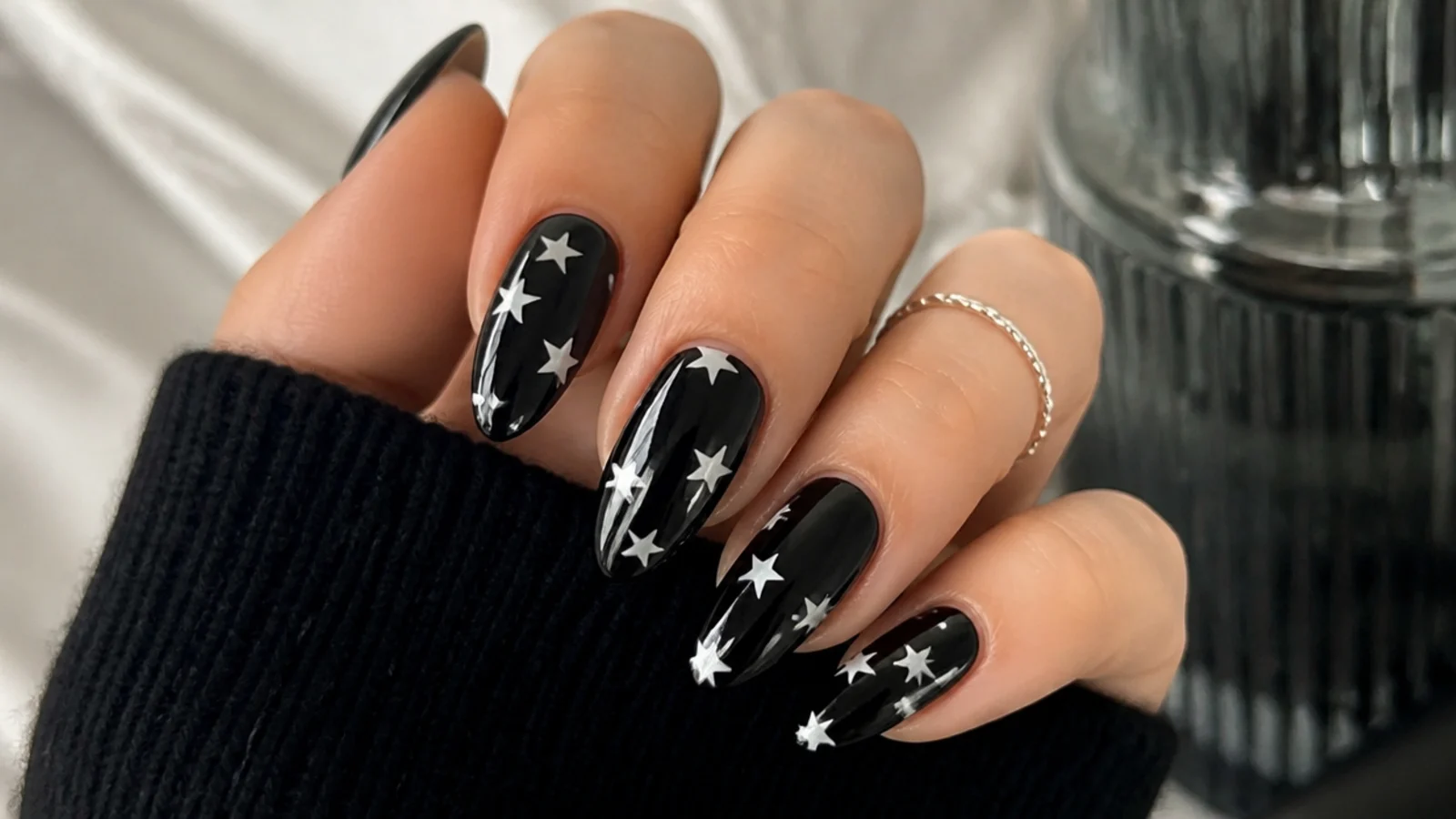 Glossy black emo nails with small white five-point stars scattered