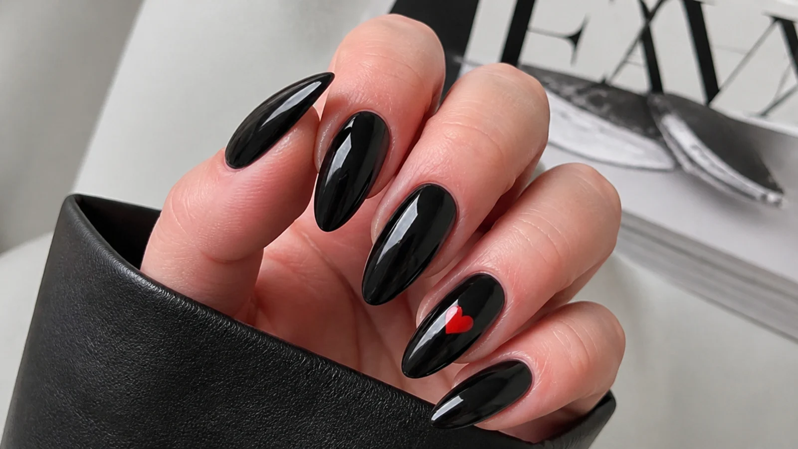 Glossy black emo nails with a single small red heart accent