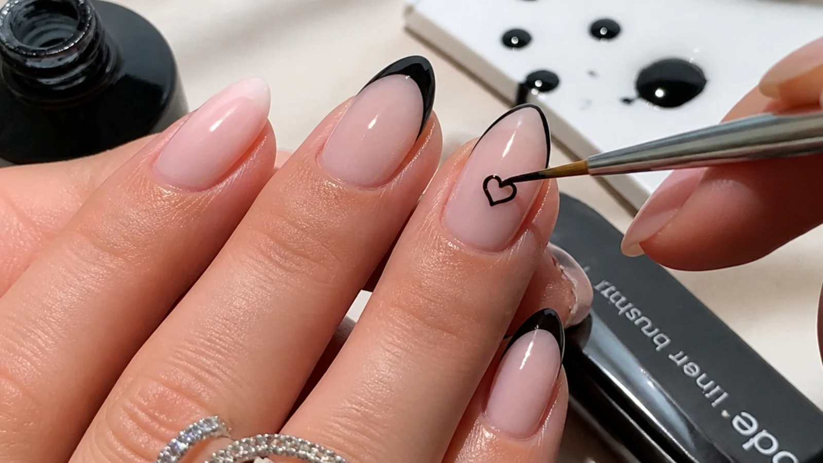At-home emo nail supplies with a thin liner brush drawing a black heart
