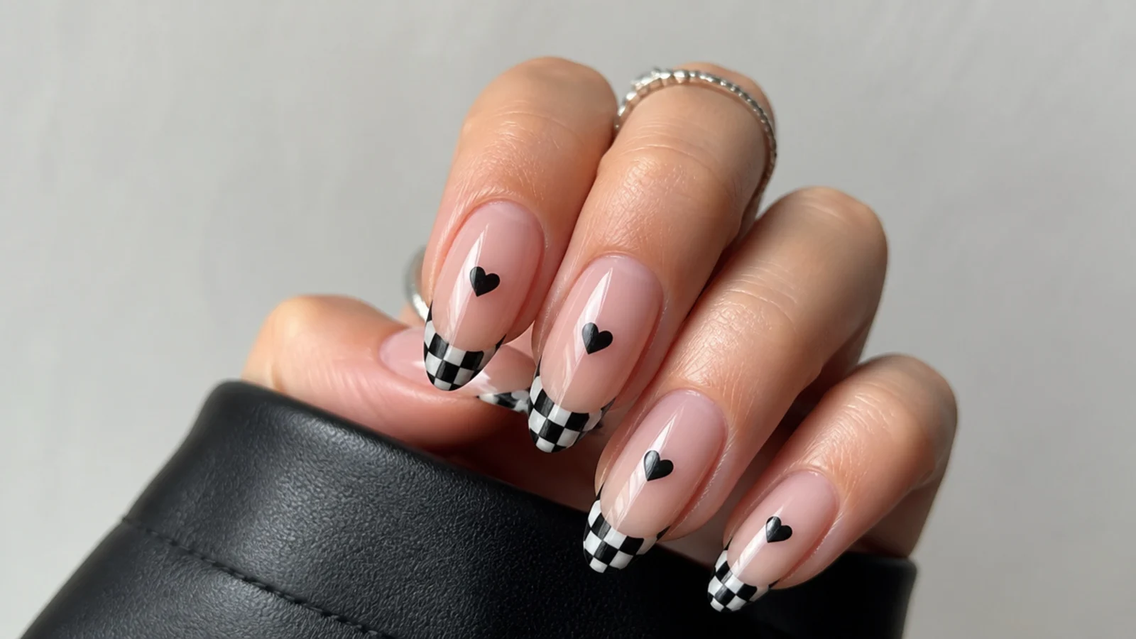 Simple emo nails with small black hearts and checkerboard tips on almond nails