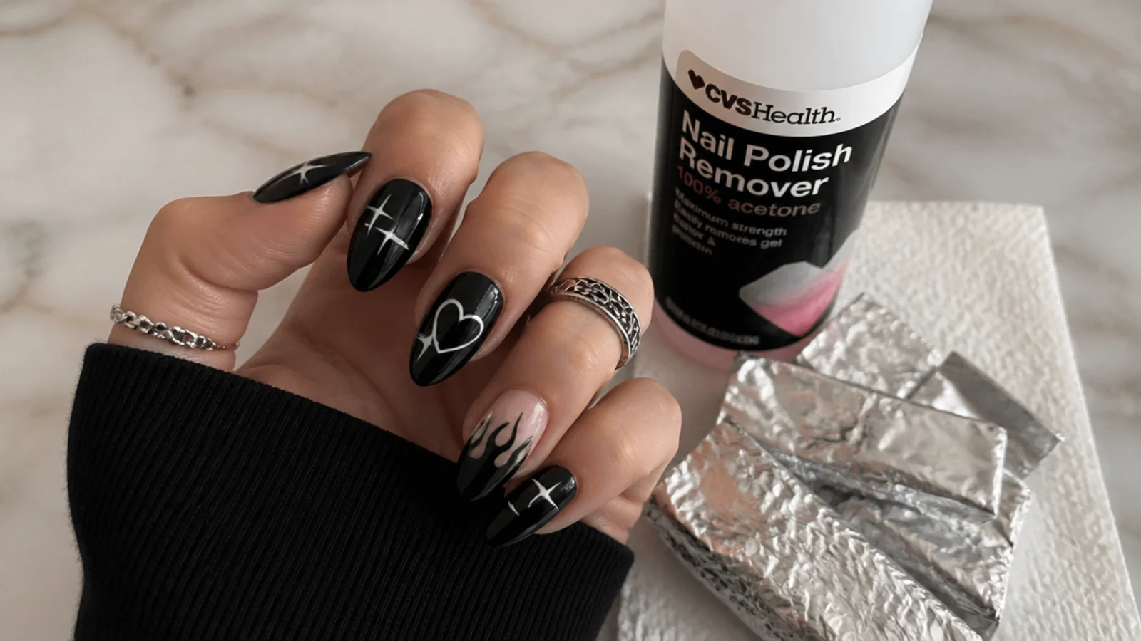 A sealed black emo manicure beside acetone and foil for safe removal