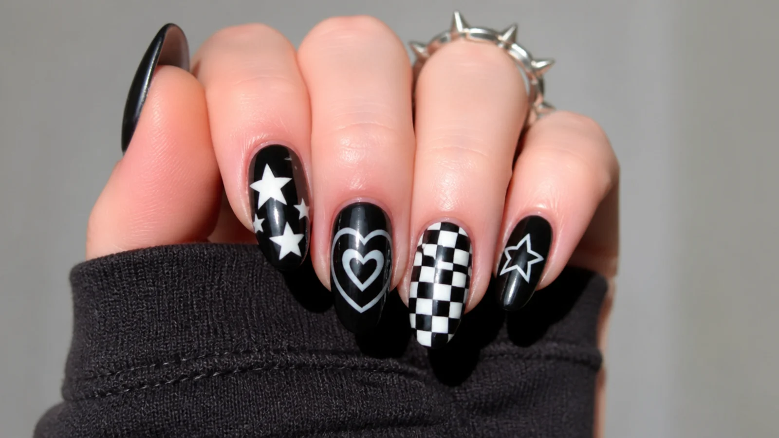 Emo nails with black base, white stars, hearts and checkerboard motifs