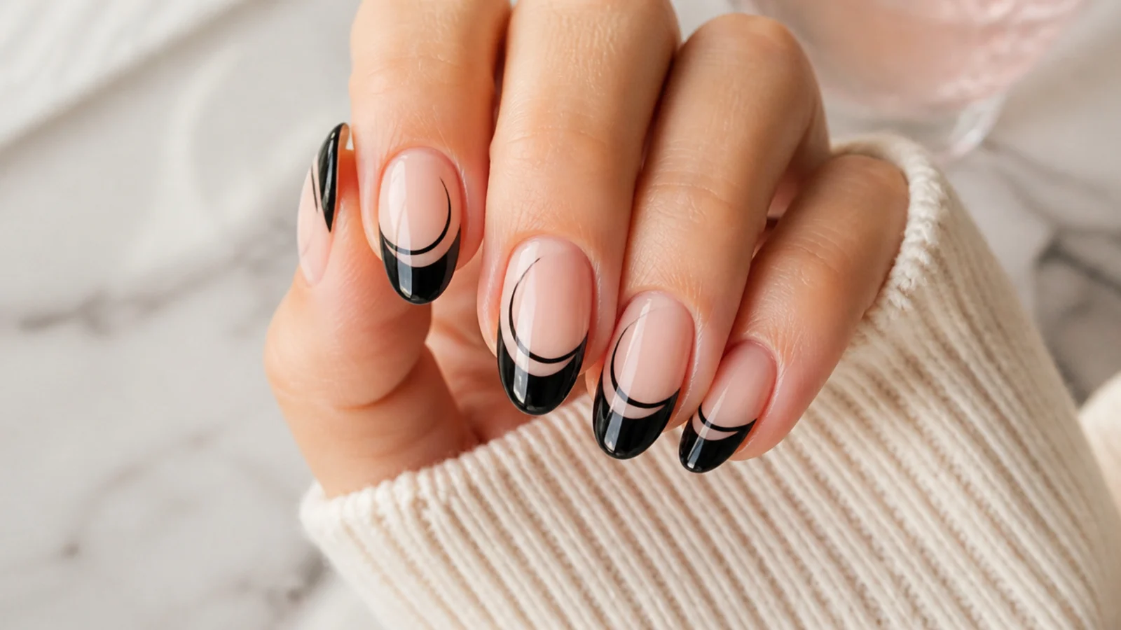Almond nails with a graphic black French tip on a clear base and a deep curved line