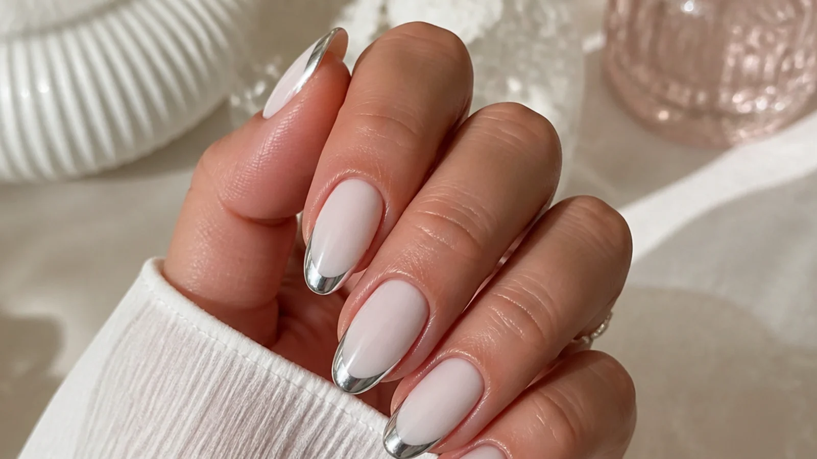 Almond nails with a silver chrome mirror French tip over a milky white base