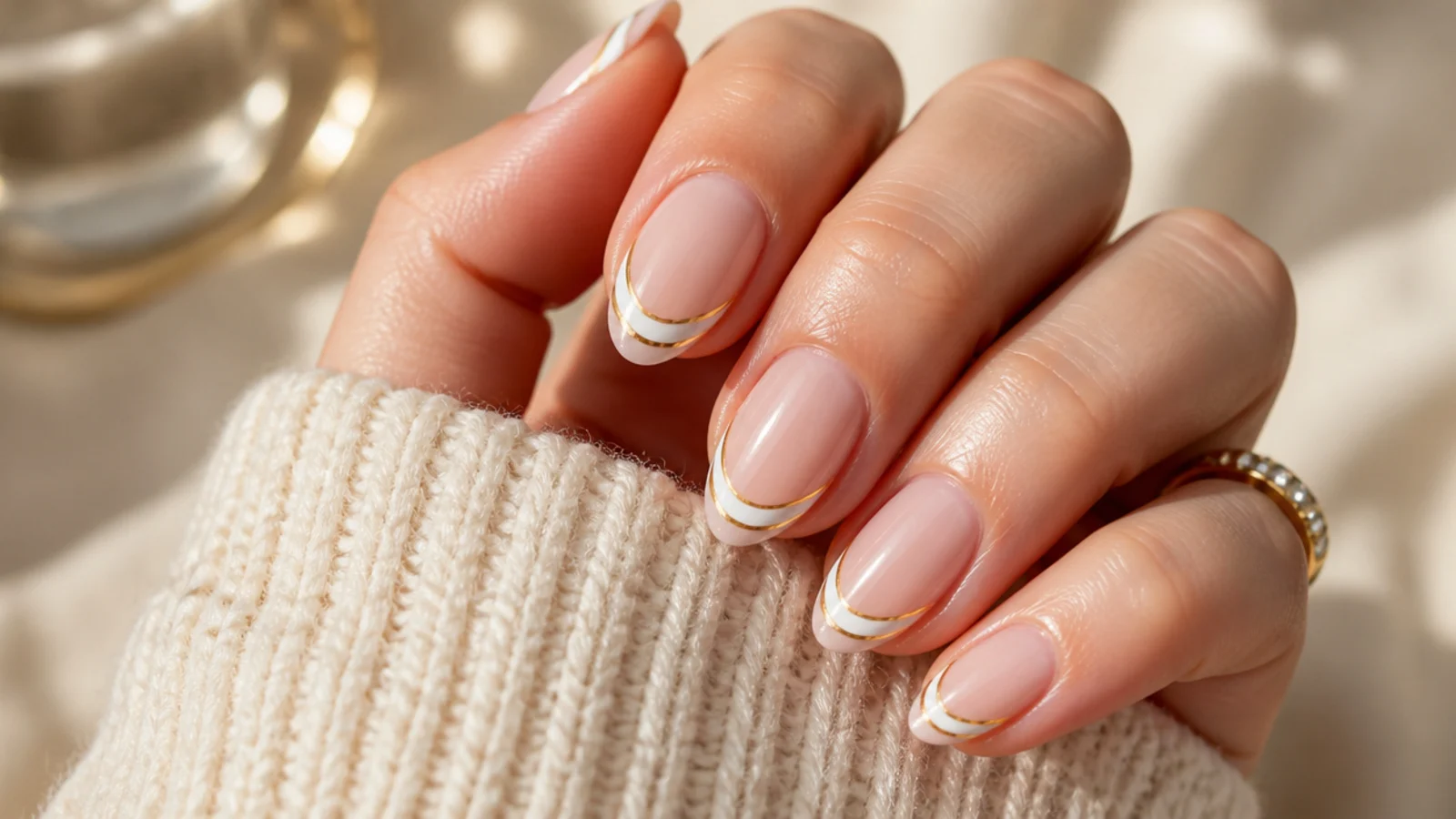 Almond nails with two stacked curved French lines in white and gold along the tip