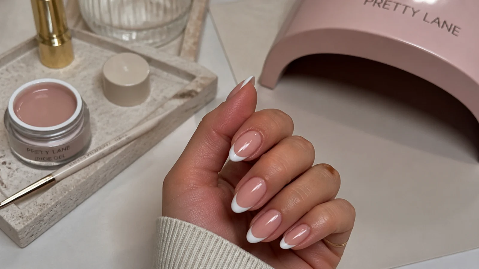Nail salon station with liner brush, nude gel and lamp set up for almond French tips