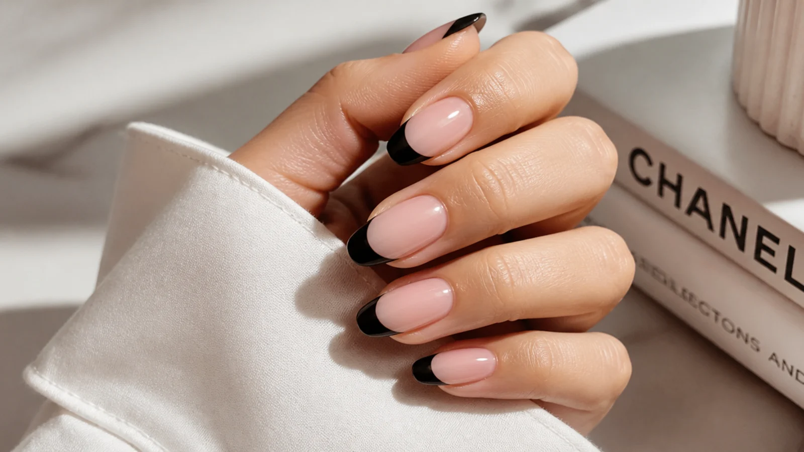 Medium almond nails with a classic black French tip over a sheer pink nude base