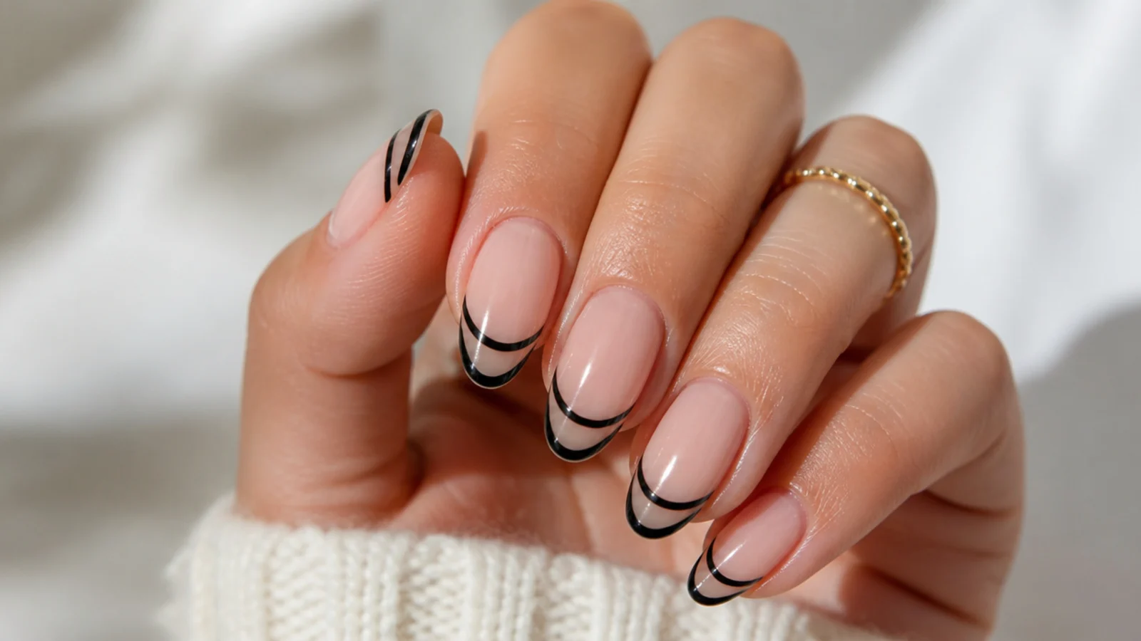 Almond nails with a double black French tip showing two parallel curved lines at the edge
