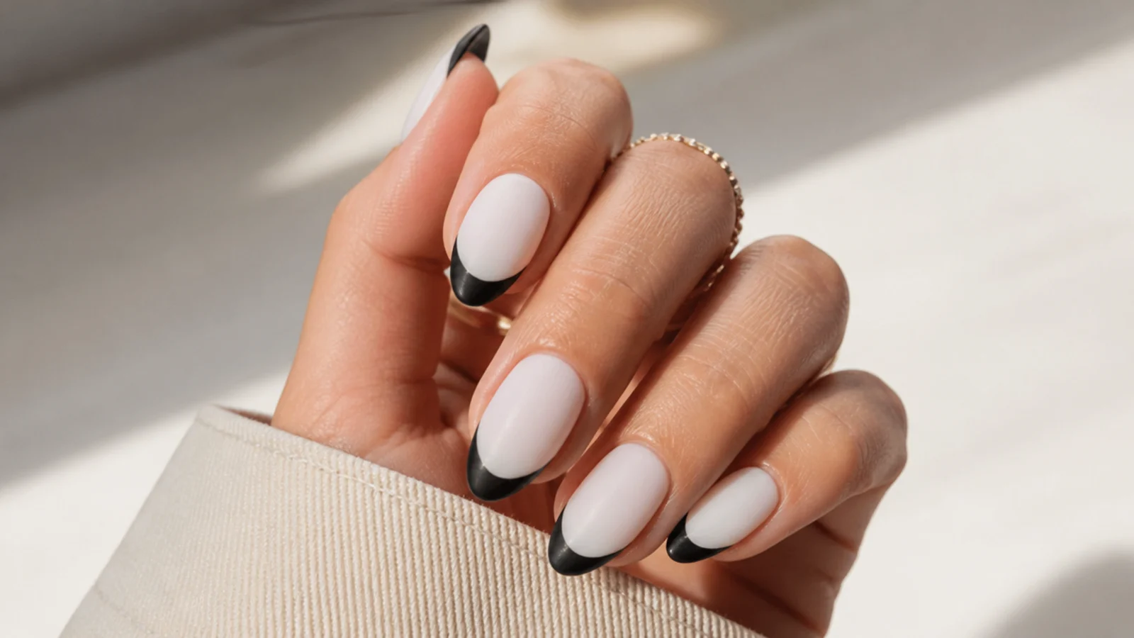 Almond nails with matte black French tips over an opaque milky white base