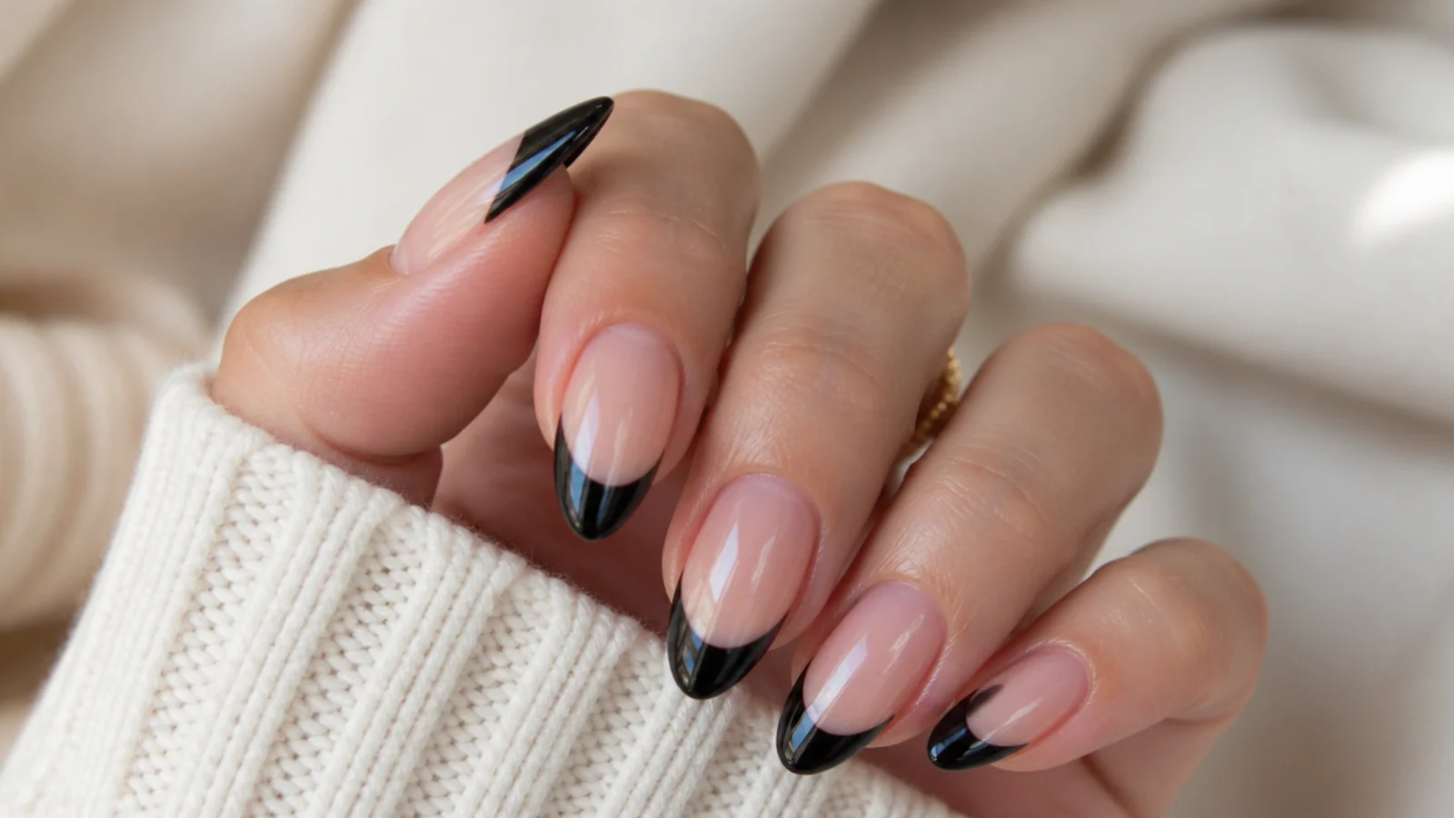 Long almond nails with high-gloss black French tips reflecting light along the smile line