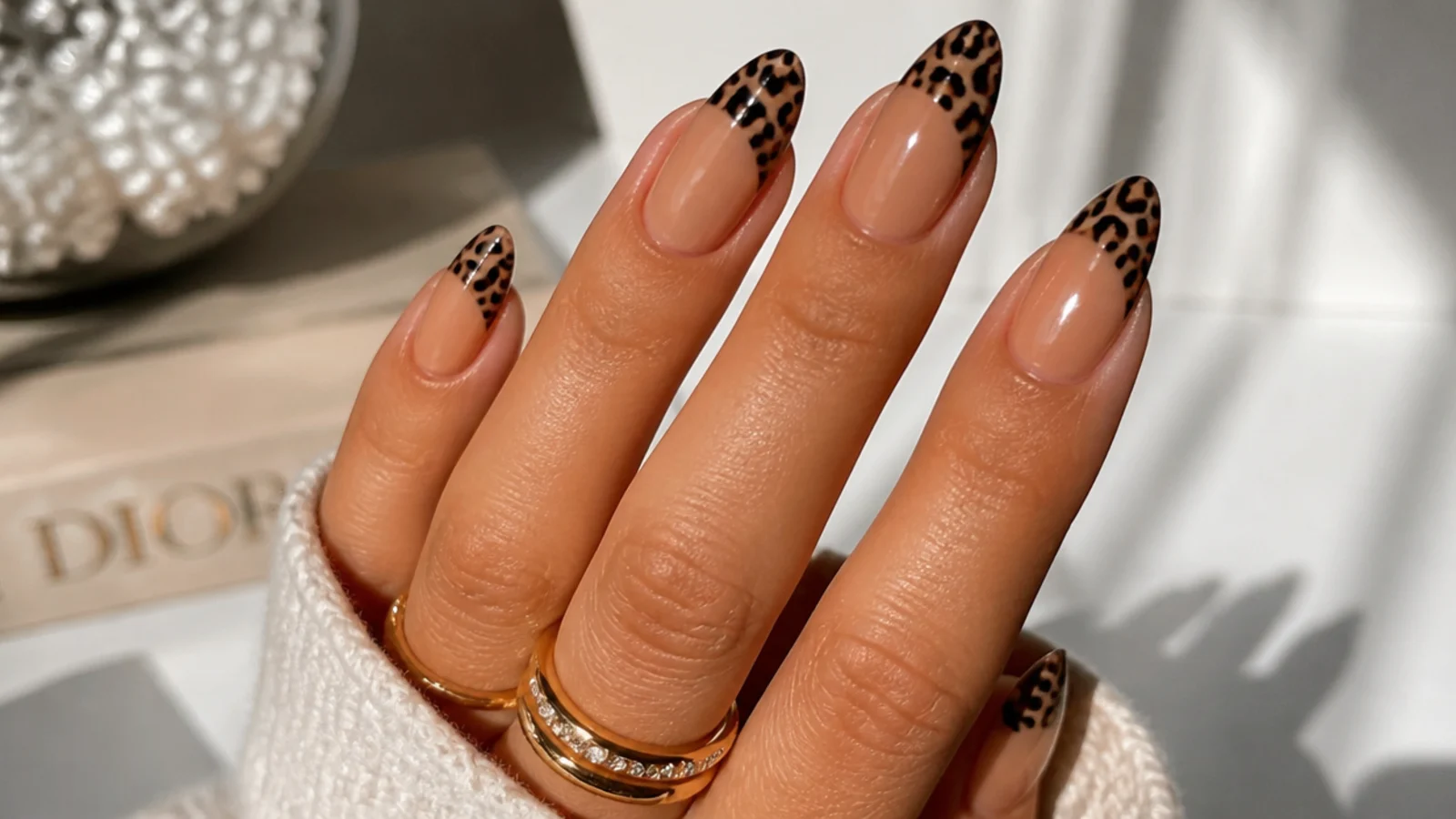 Medium almond nails with black leopard print spots filling the French tip over a caramel base