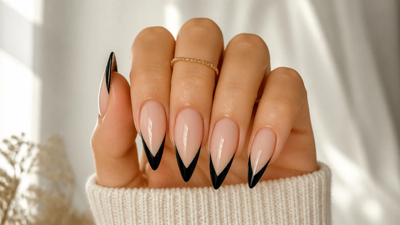 Long stiletto nails with black French tips forming a sharp V at the point