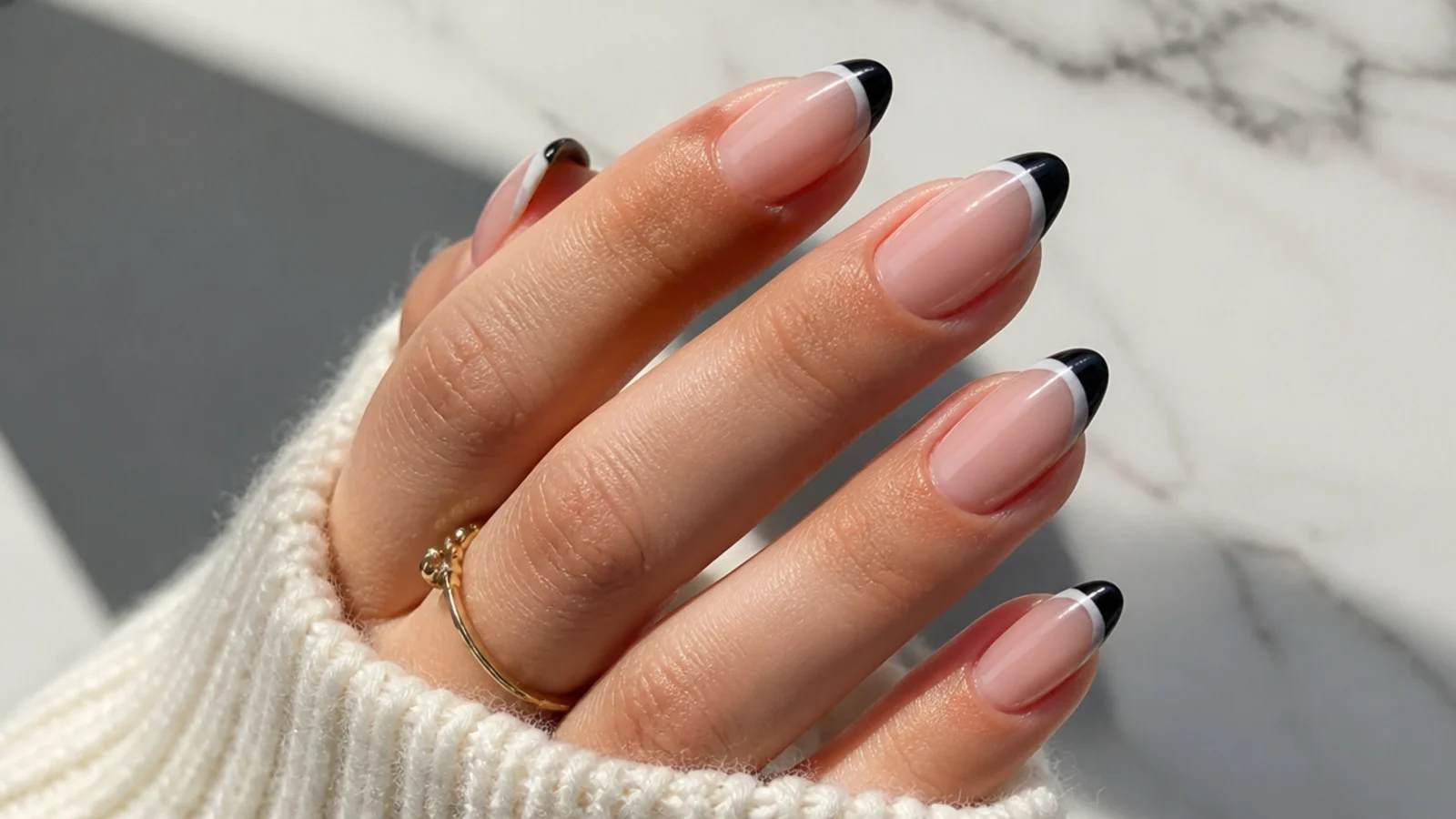 Almond nails with a black French tip and a white line beneath it in a monochrome split