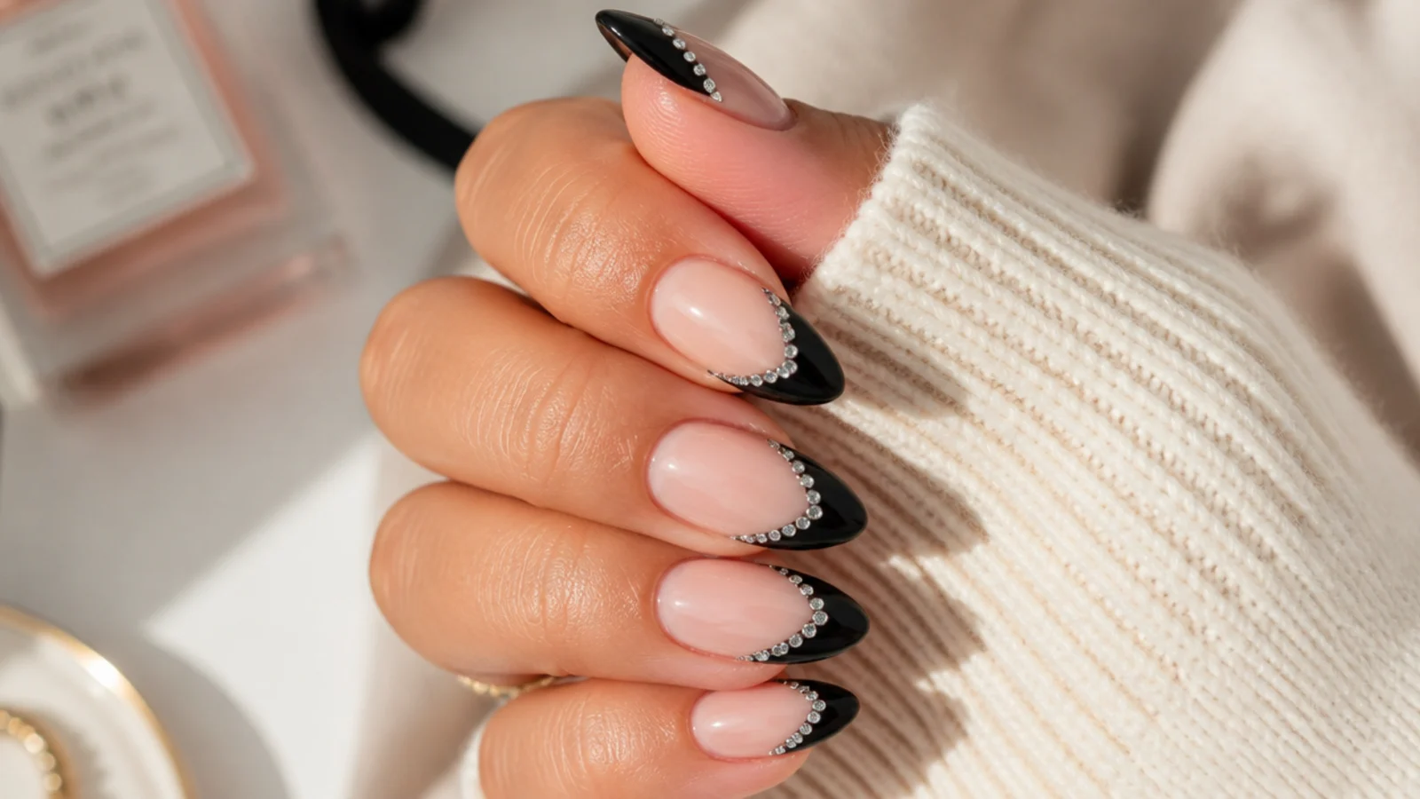 Long almond nails with black French tips edged by a row of tiny clear rhinestones