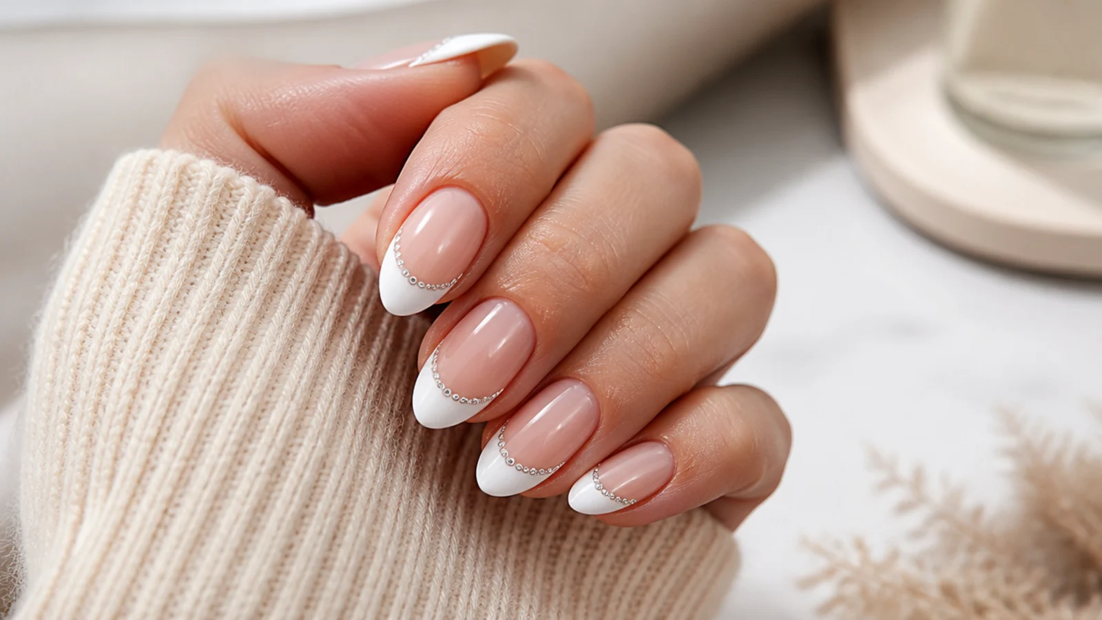 Medium almond nails with white French tips and small clear rhinestones set along the smile line