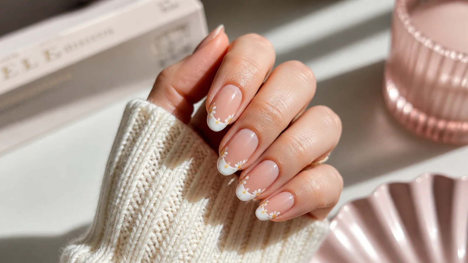 Medium almond French tip nails with a white smile line and tiny hand-painted daisies on the tip