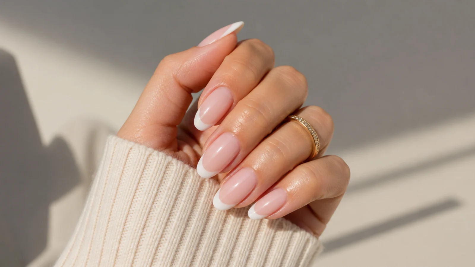 Almond nails with soft milky white French tips fading into a translucent nude base