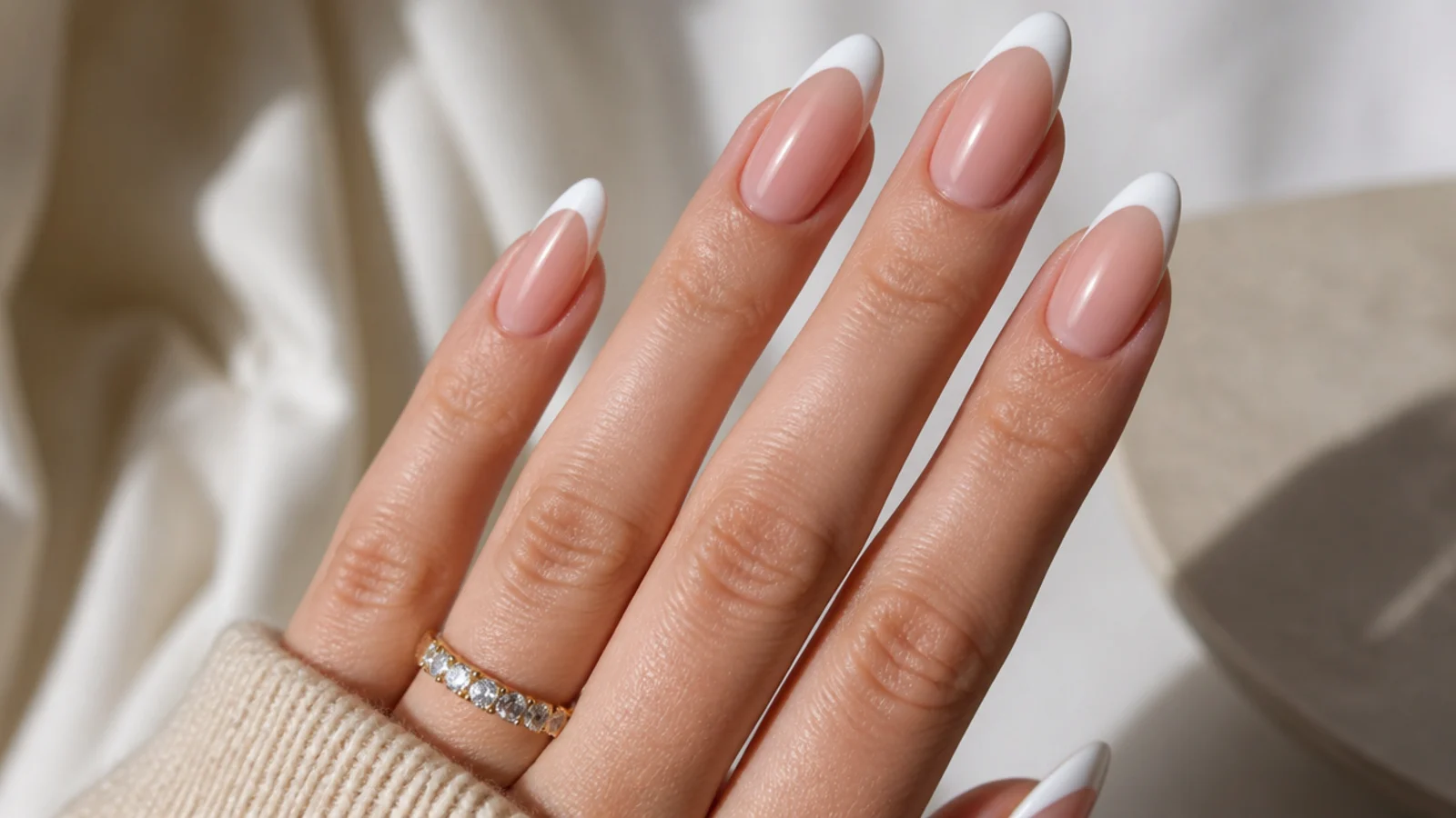 Long almond nails with a curved white French tip following the taper toward a rounded point