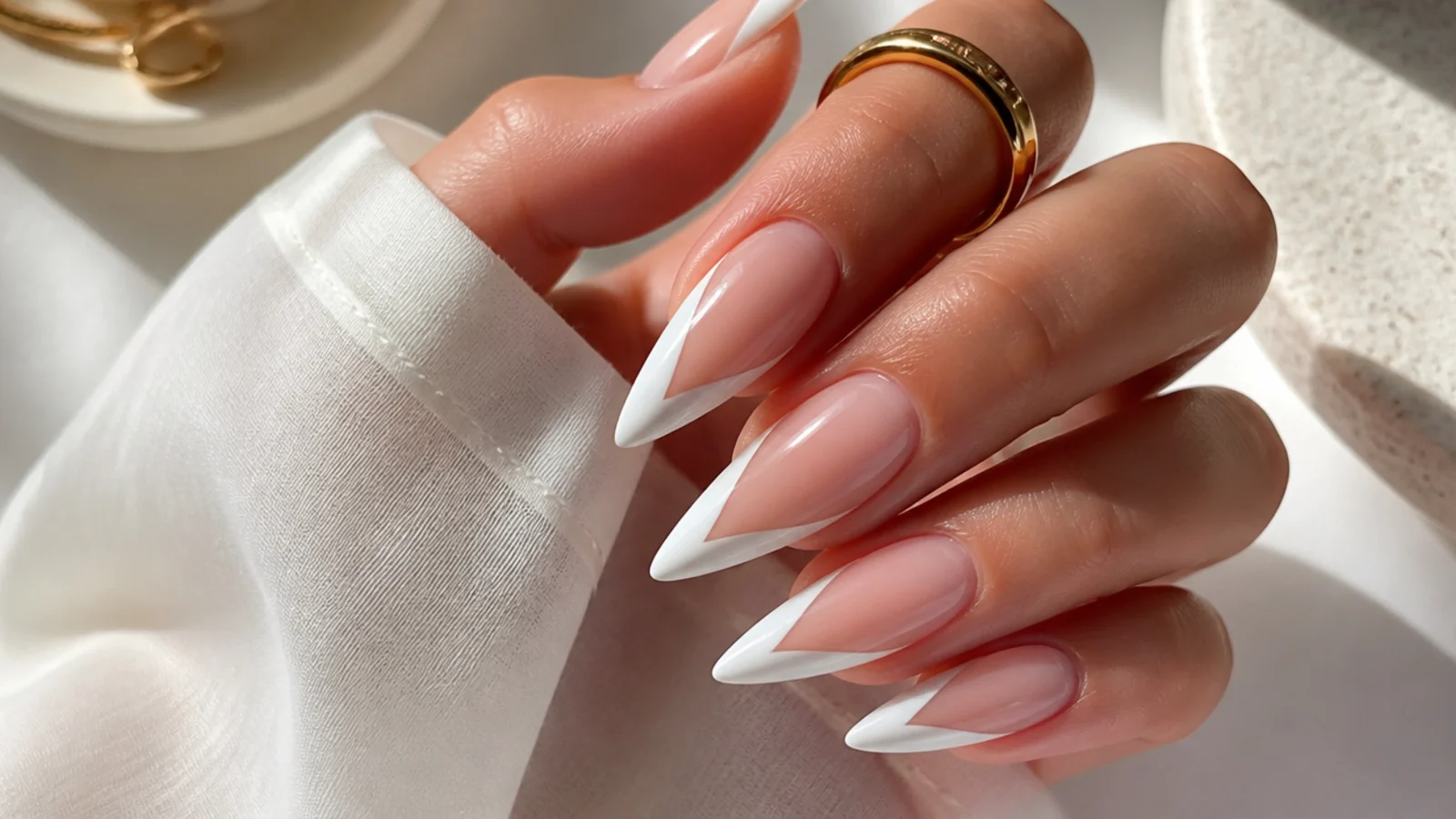 Long stiletto nails with a deep V shaped French tip painted in white over a sheer base