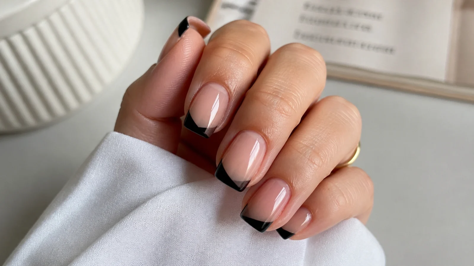 Square nails with an angled diagonal French tip painted in black across the free edge