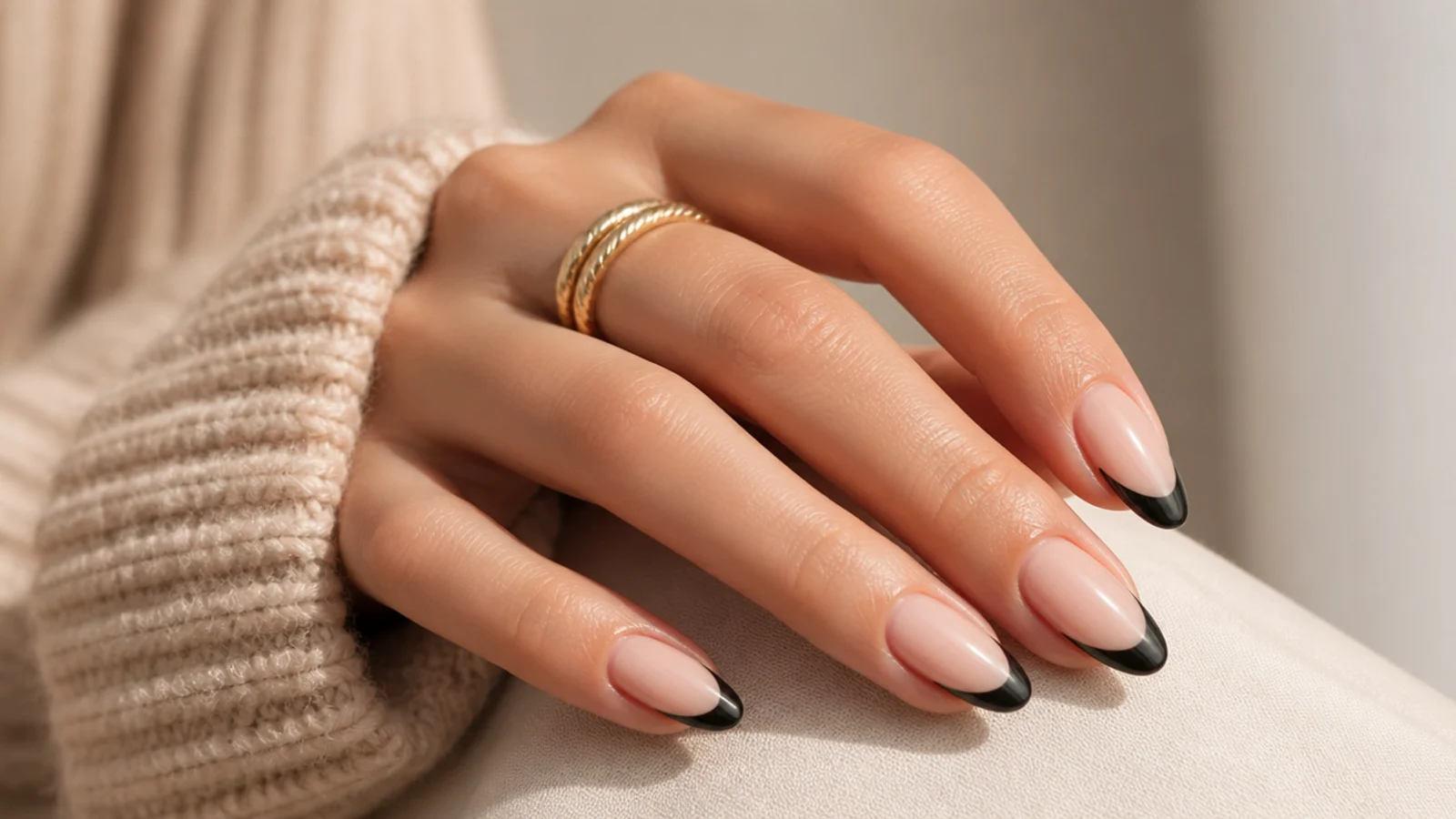 Almond nails with glossy black French tips over a sheer nude base and a crisp smile line