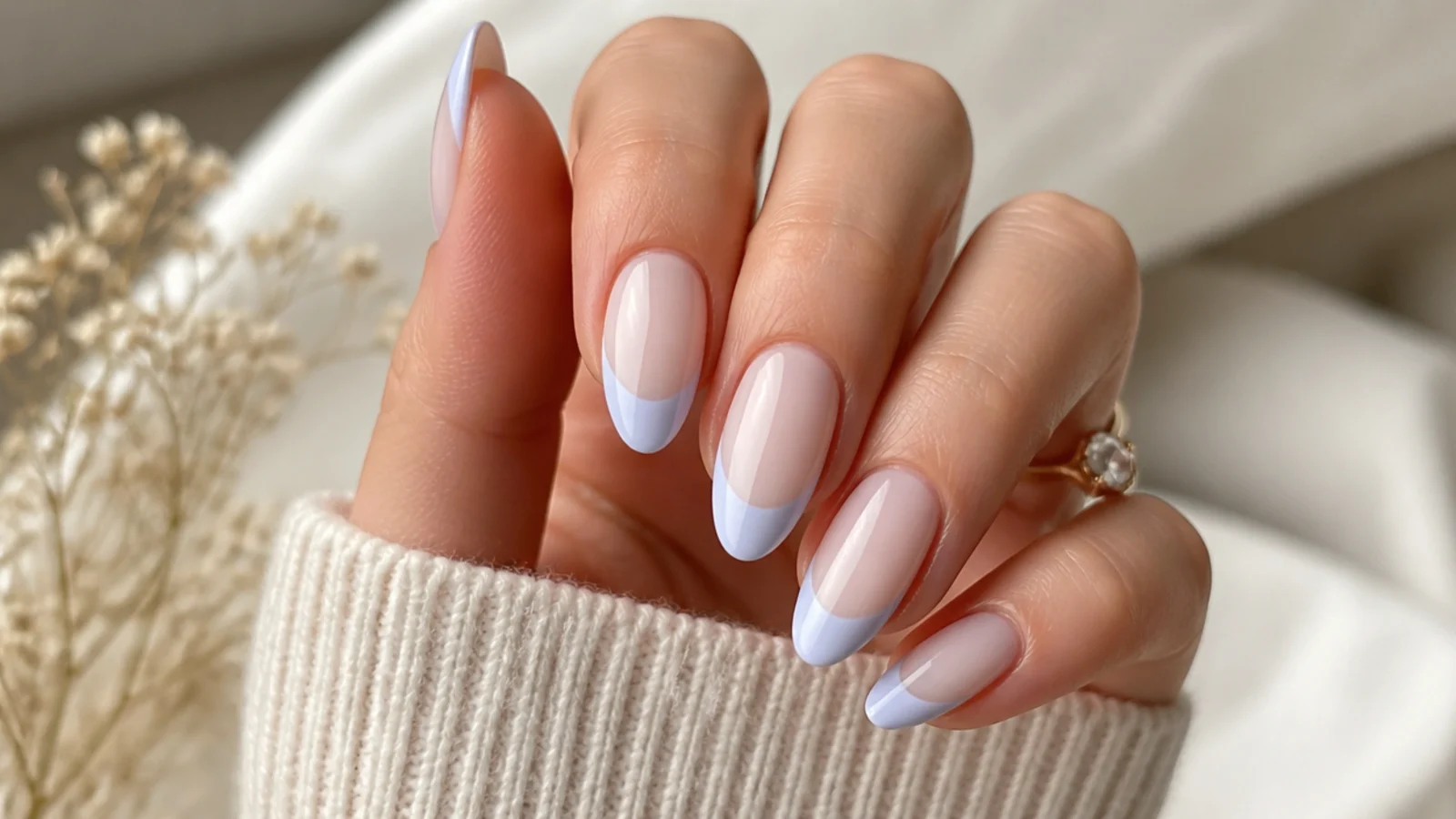Almond nails with pale baby blue French tips over a sheer milky base