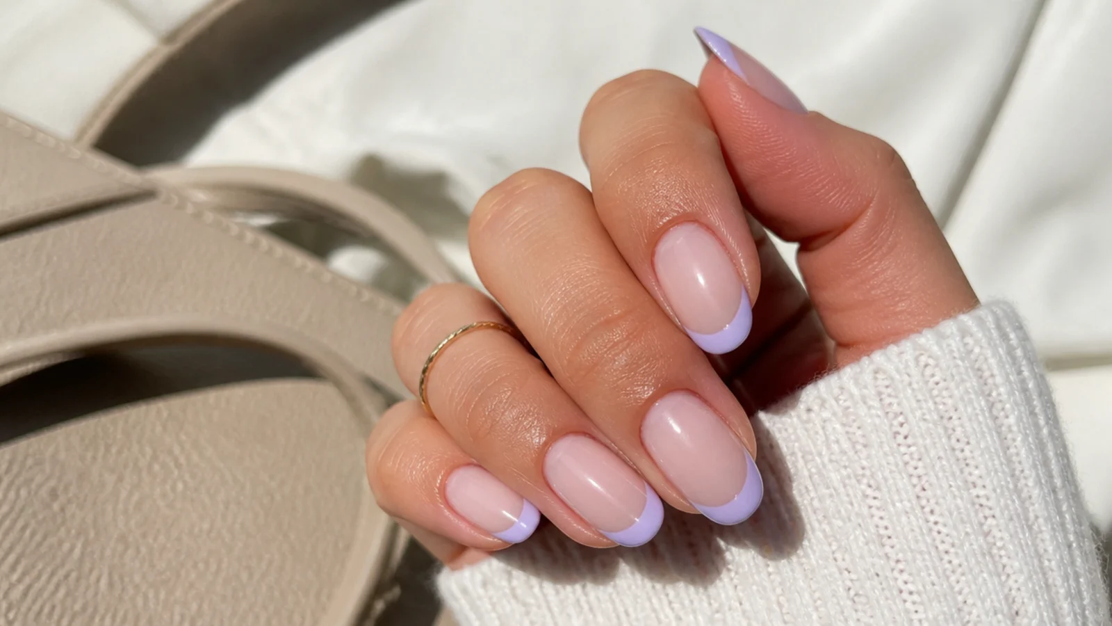 Short almond nails with soft lavender French tips over a translucent nude base