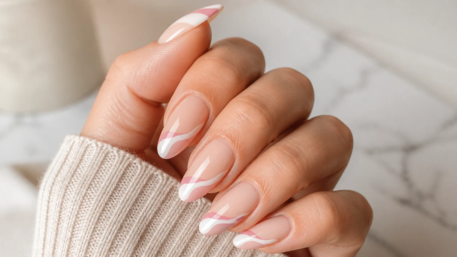 Almond nails with a wavy swirled French tip line curving diagonally across a nude base