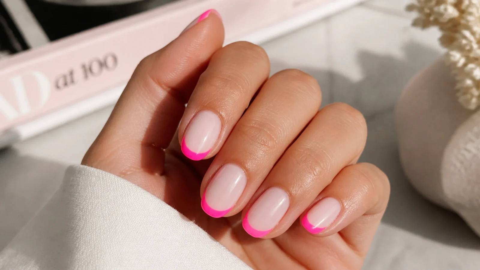 Short almond nails with neon pink French tips on a sheer milky base