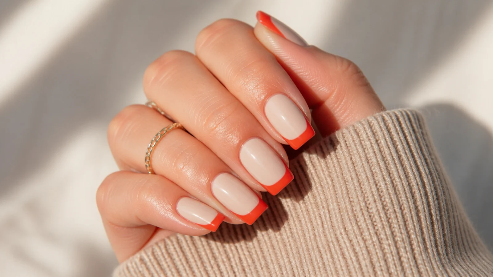 Medium square nails with warm tomato red French tips on a warm beige base