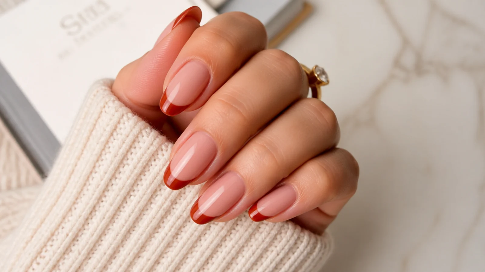 Medium almond nails with muted brick red French tips over a warm nude base