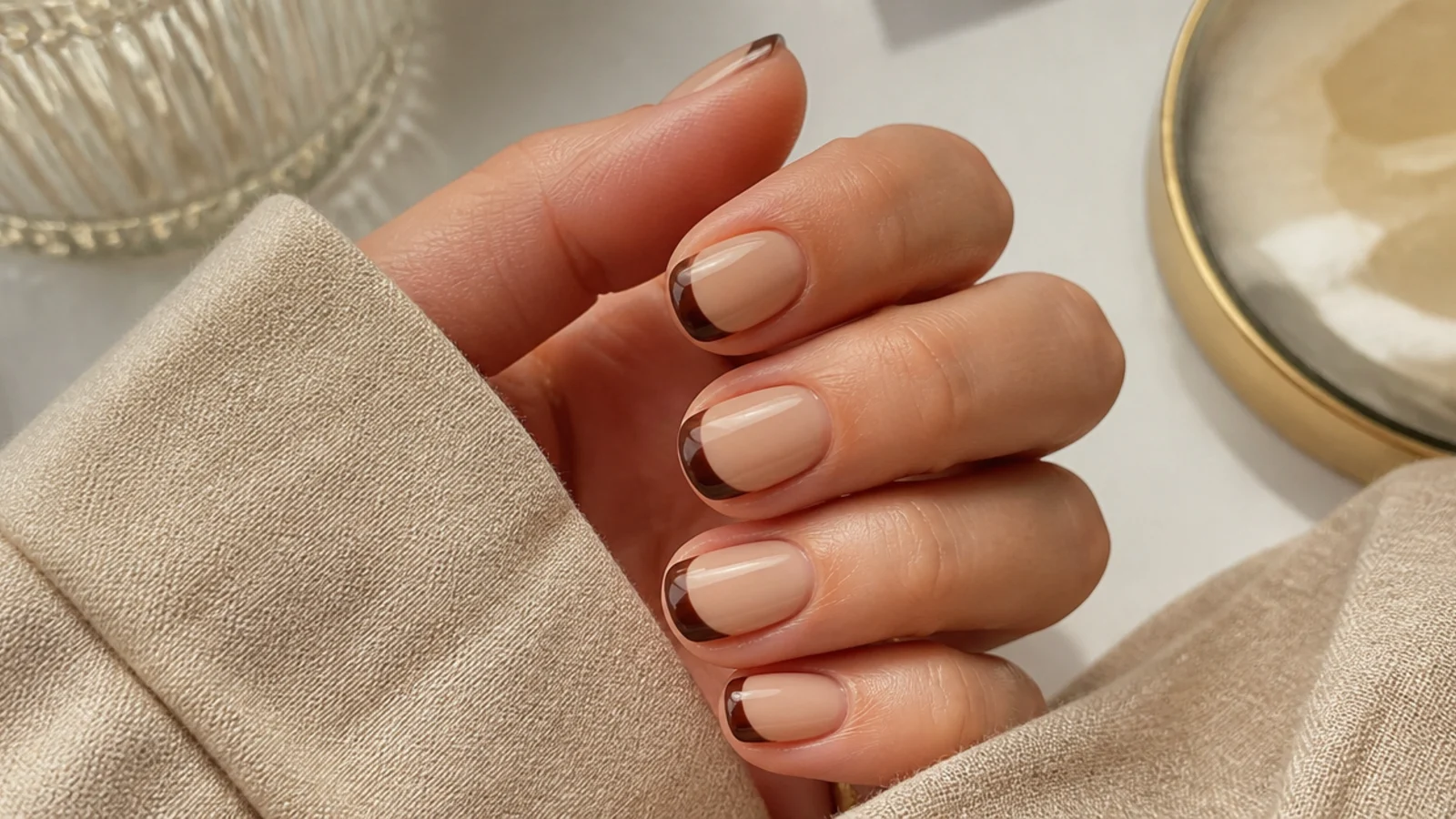 Short nails with an espresso brown French tip over a warm beige base