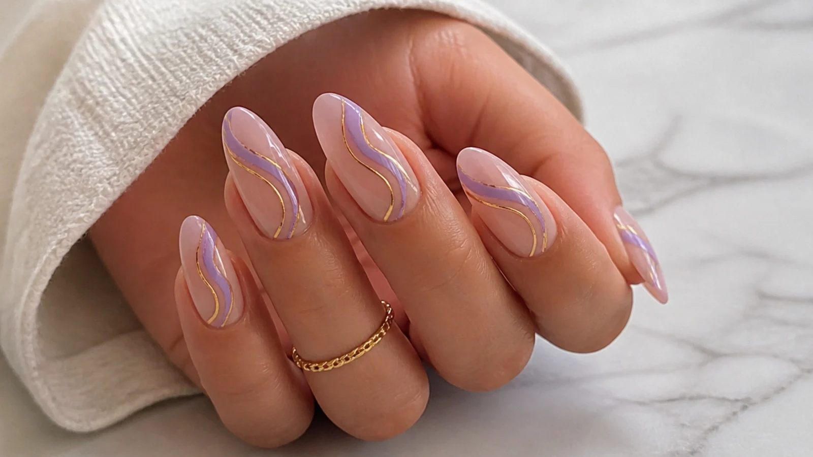 Nude nails with lavender and gold swirl line art on almond shape