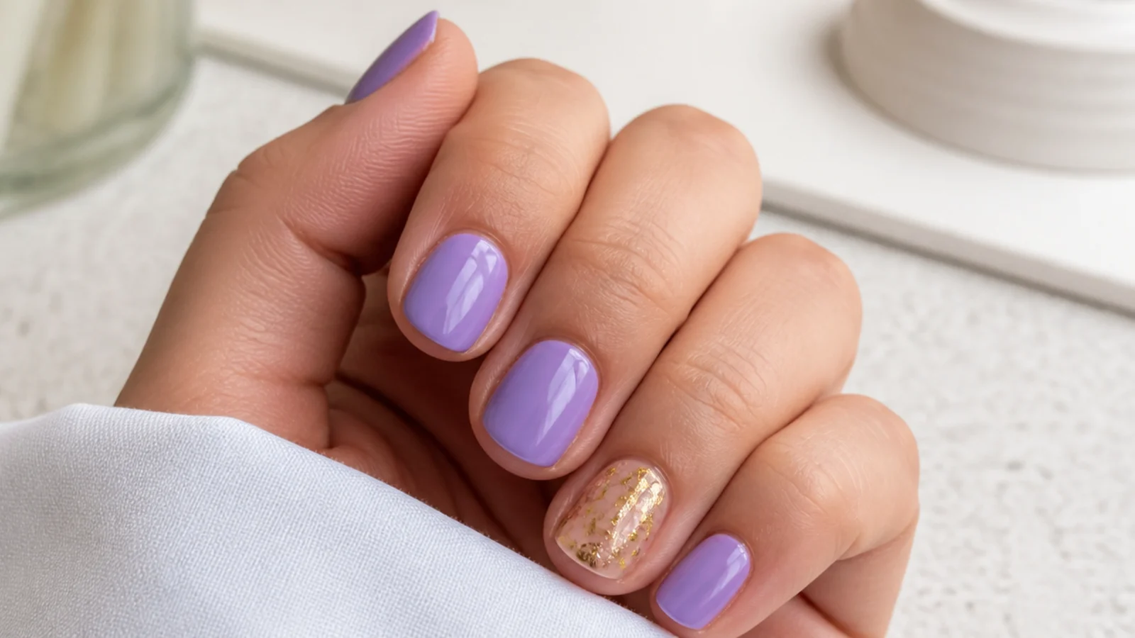 Short lavender nails with one gold foil accent nail