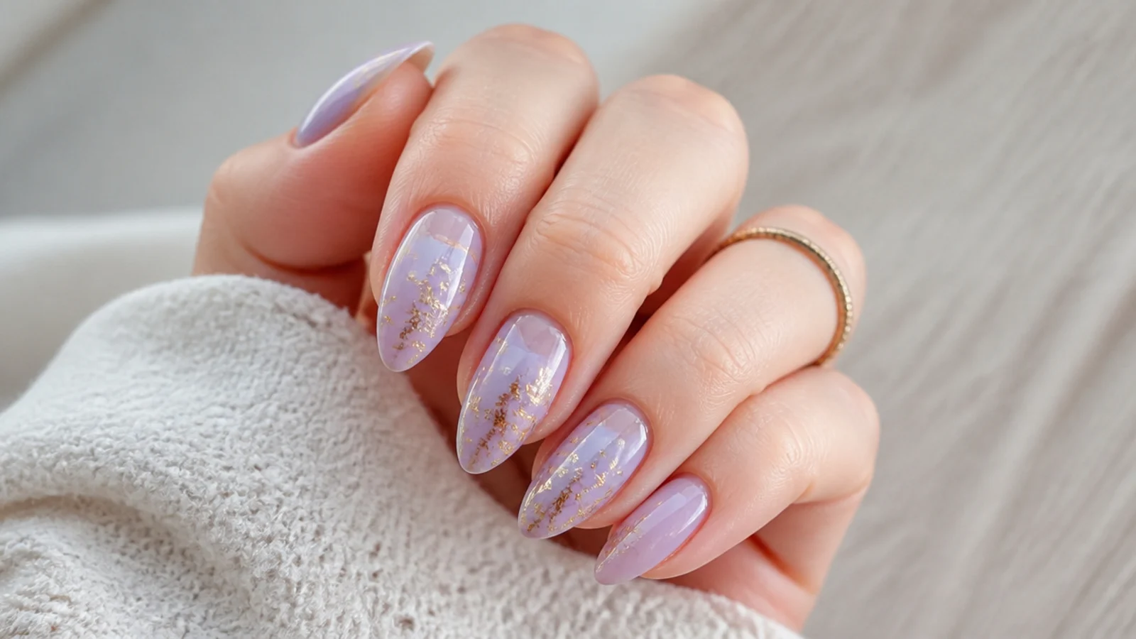 Soft lavender nails with gold foil accents on an almond shape