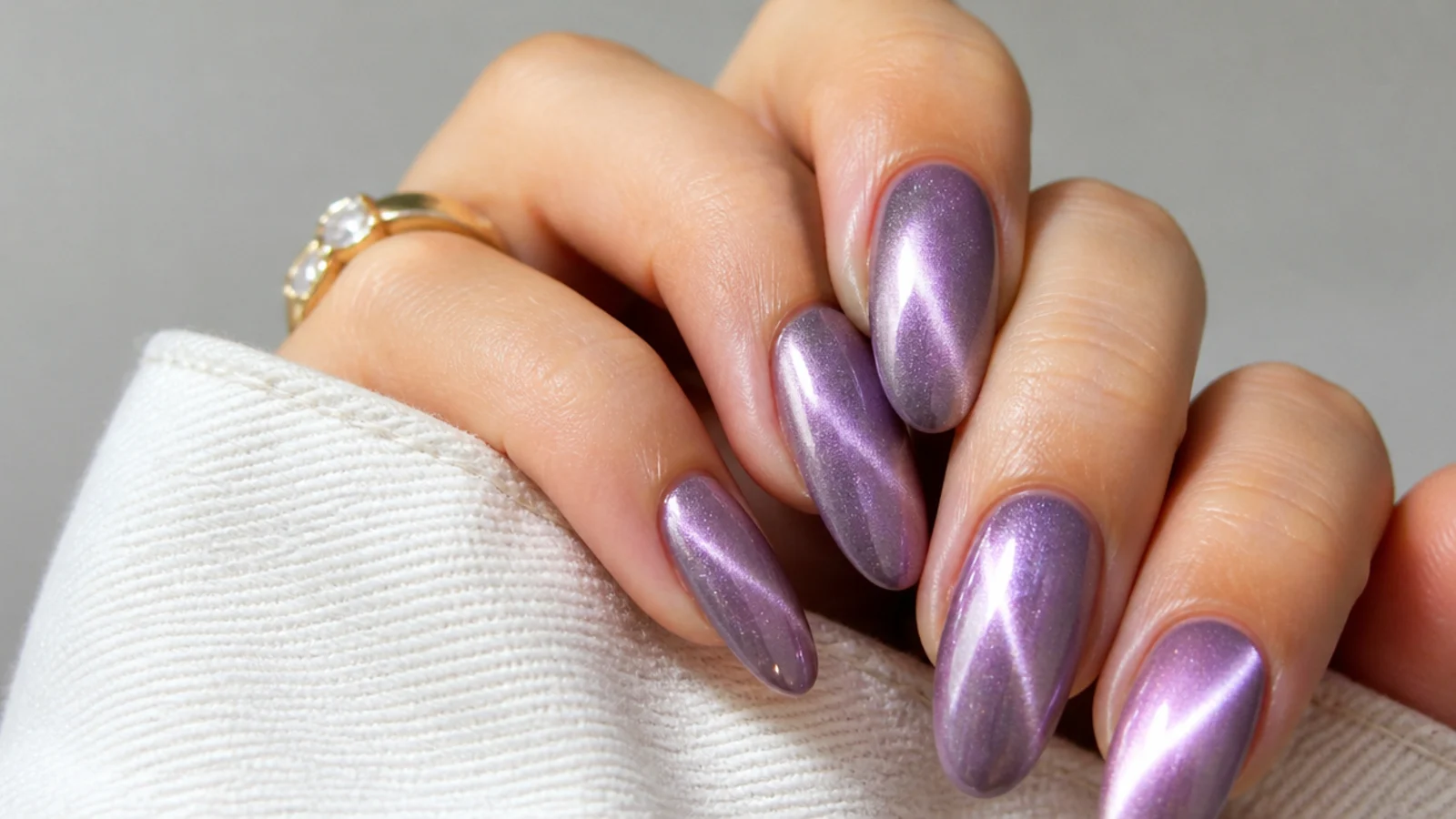 High-shine lavender chrome cat eye nails with a curved swirl of light