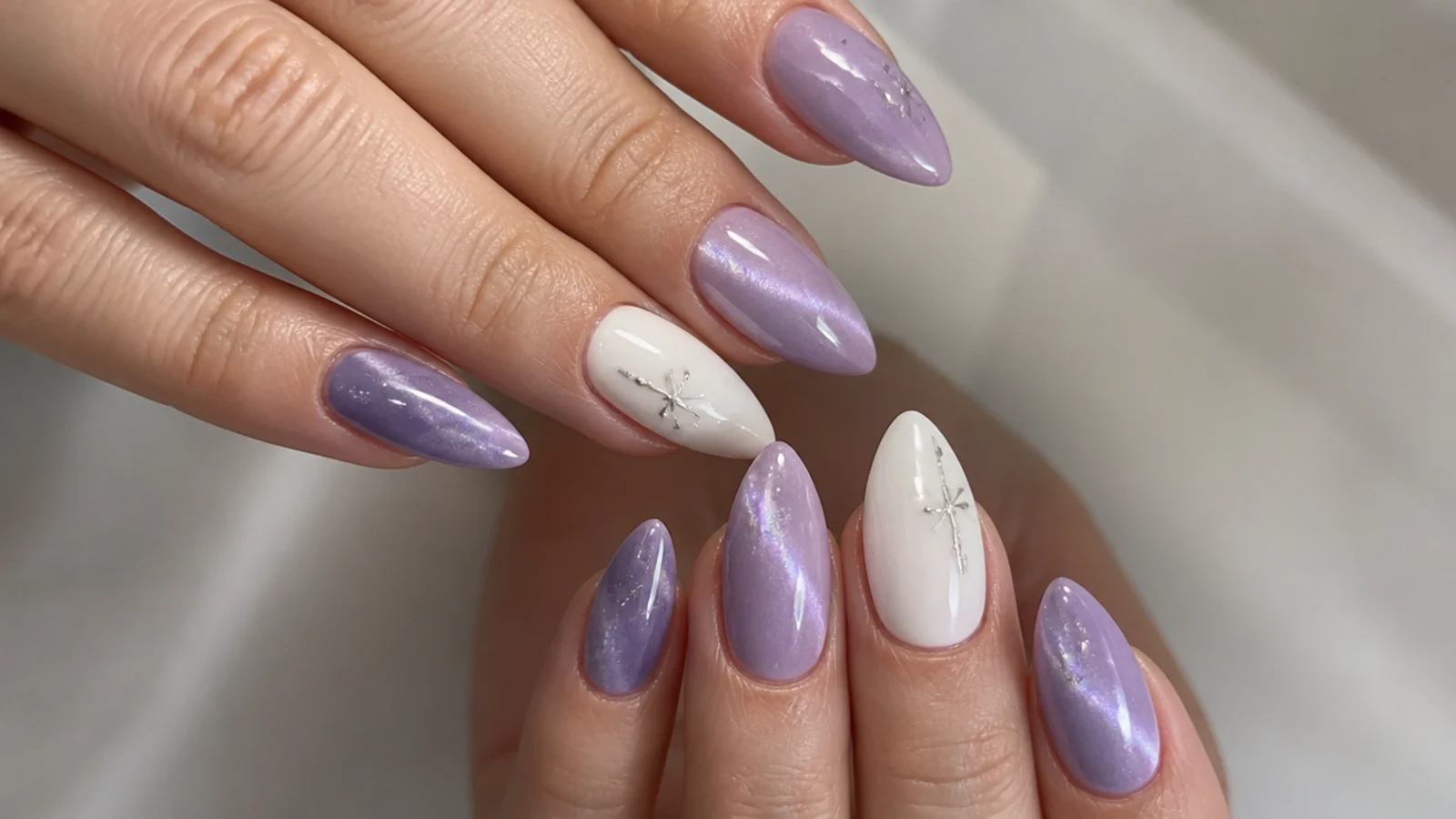 Lavender cat eye nails with clean white accent nails on an almond shape