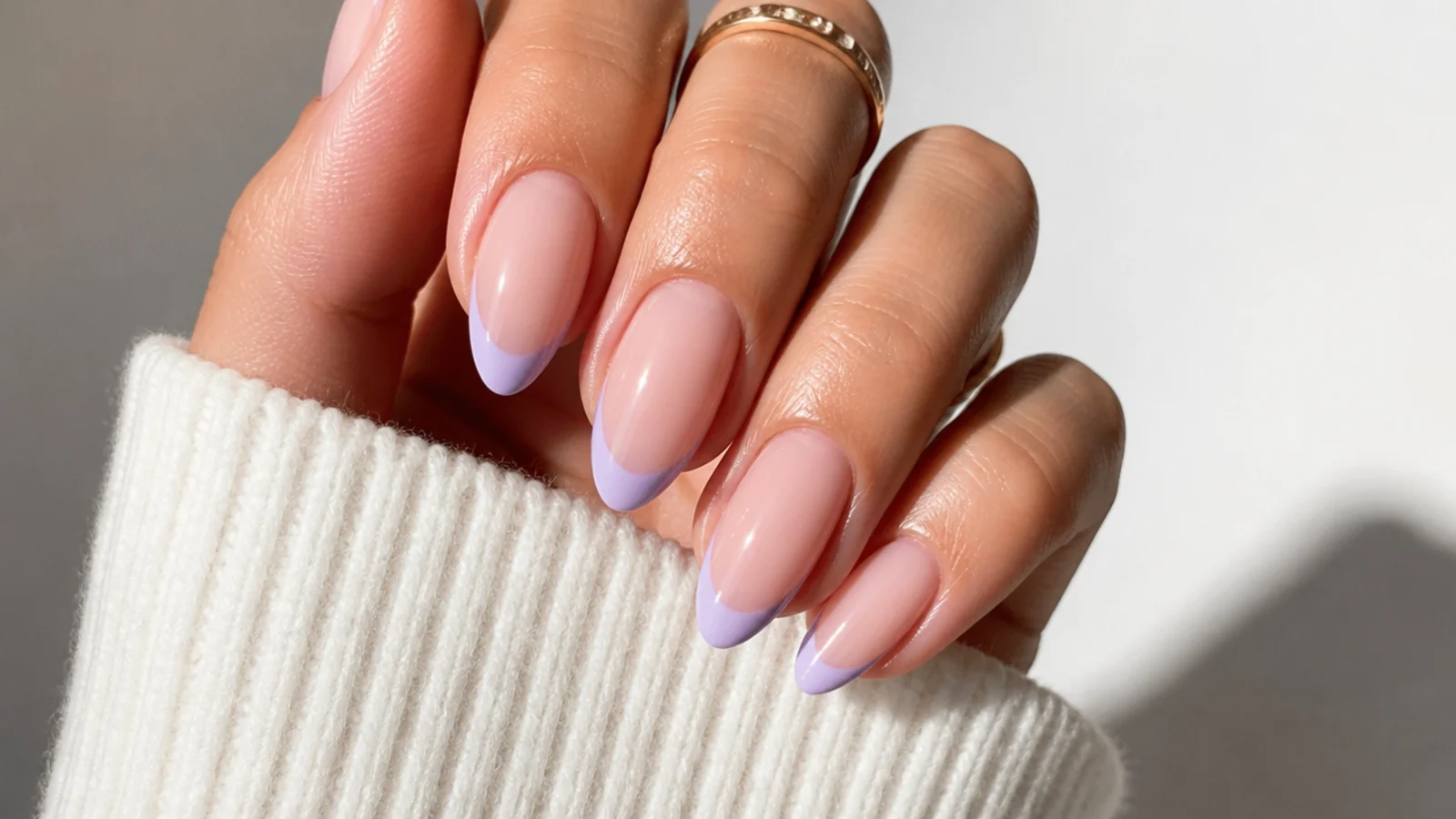Milky nude nails with soft lavender French tips on an almond shape