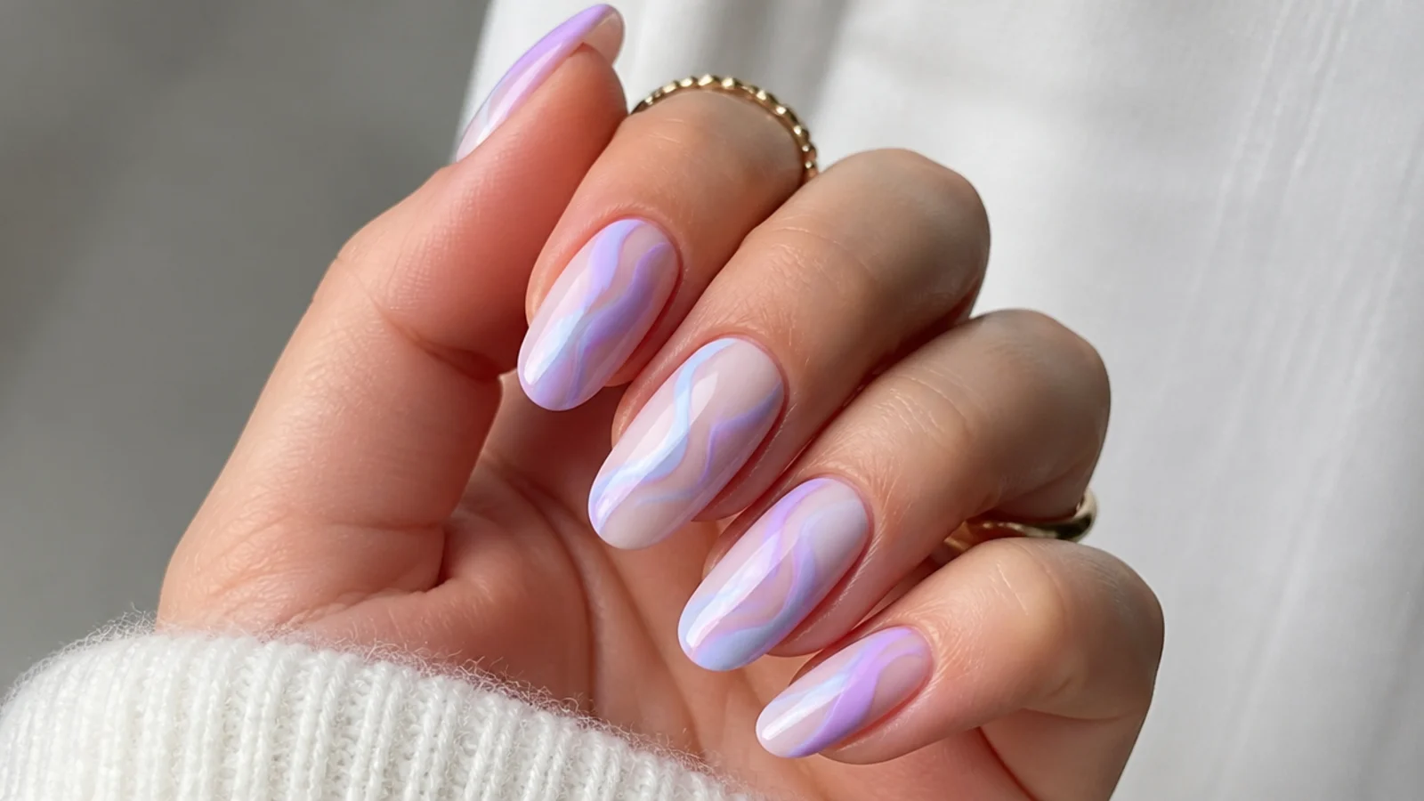 Lavender nails with soft baby blue swirls painted across a milky base