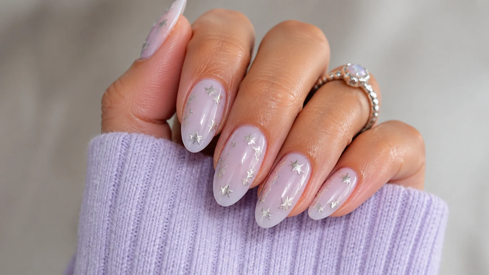 Lavender nails with small silver star decals scattered on a milky base